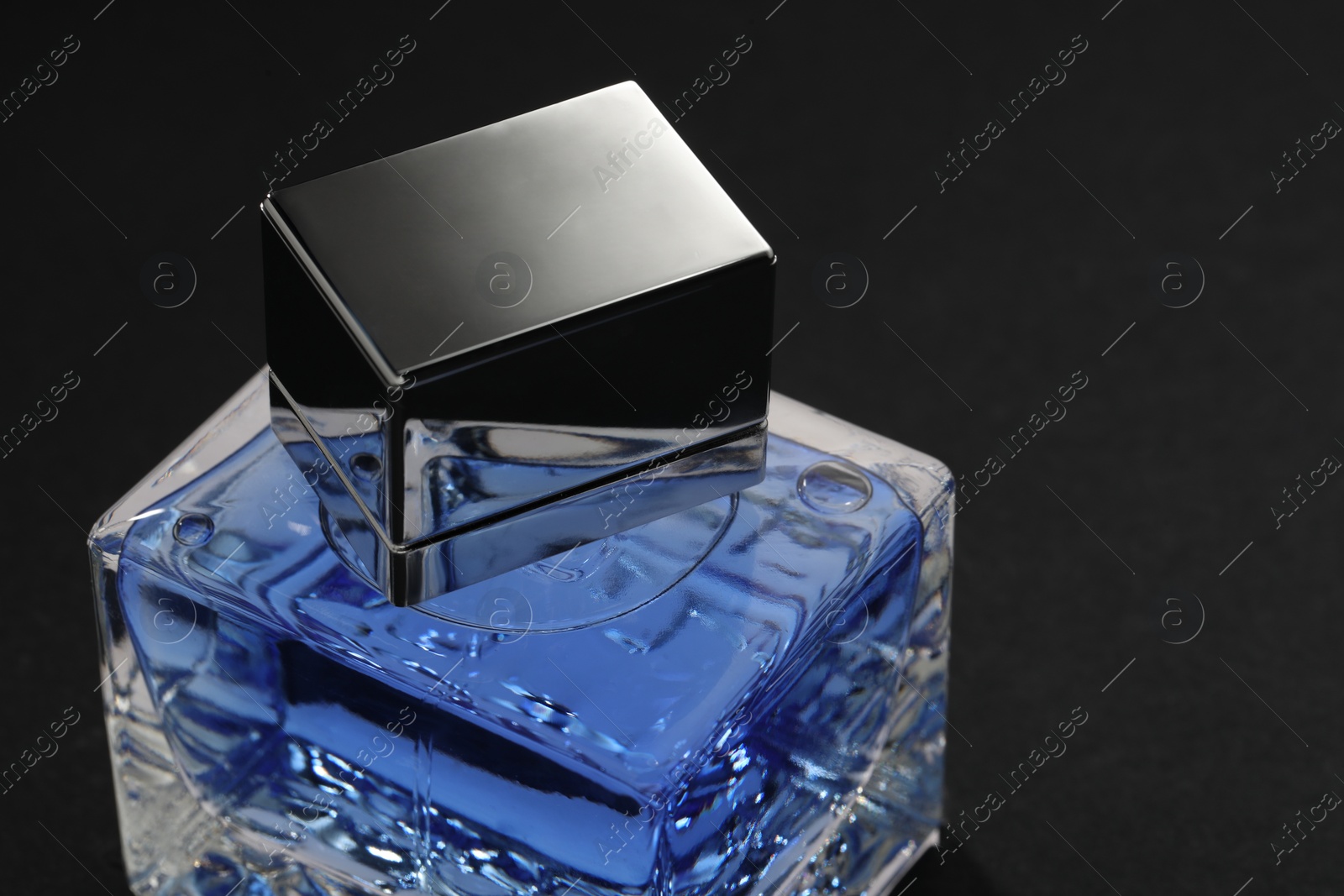 Photo of Blue men's perfume in bottle on black background, closeup