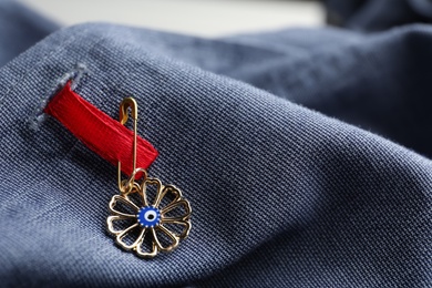 Photo of Evil eye safety pin on clothing, closeup