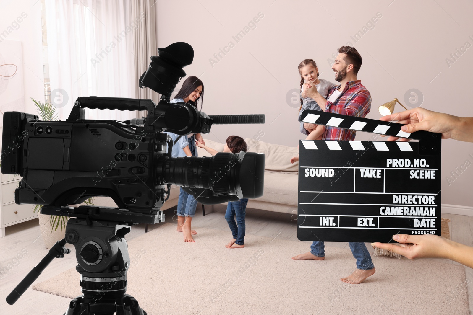 Image of Shooting movie. Second assistant camera holding clapperboard near video camera in front of happy family (actors) at home (film set)