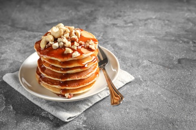 Photo of Stack of tasty pancakes with nuts and syrup on table