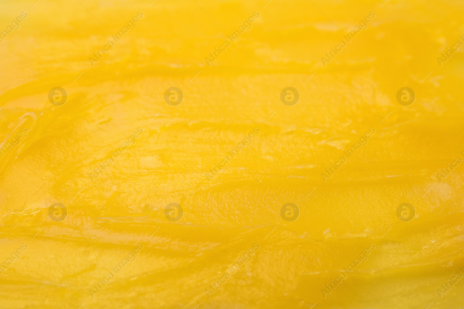 Photo of Yellow cosmetic petrolatum as background, closeup view