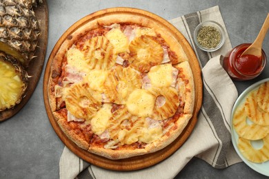 Photo of Delicious pineapple pizza and ingredients on gray table, flat lay