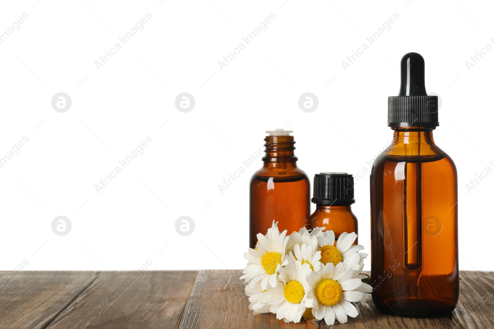 Photo of Chamomile flowers and cosmetic bottles of essential oil on wooden table against white background. Space for text