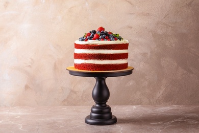 Stand with delicious homemade red velvet cake on color background