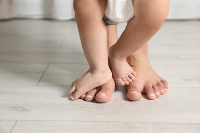 Woman and her little child standing on floor indoors, closeup. Space for text