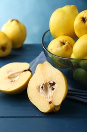 Tasty ripe quinces in bowl on blue wooden table, closeup