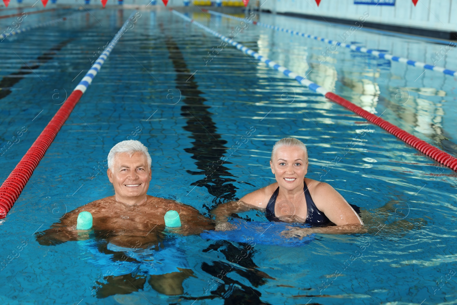 Photo of Sportive senior couple doing exercises in indoor swimming pool