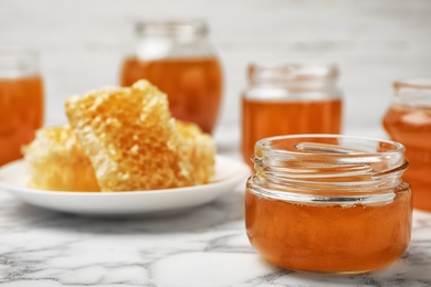 Photo of Glass jar with sweet honey on marble table