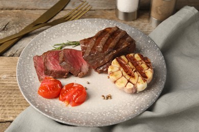 Photo of Delicious grilled beef steak with spices and tomatoes on wooden table