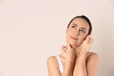 Photo of Portrait of beautiful mature woman on beige background. Space for text