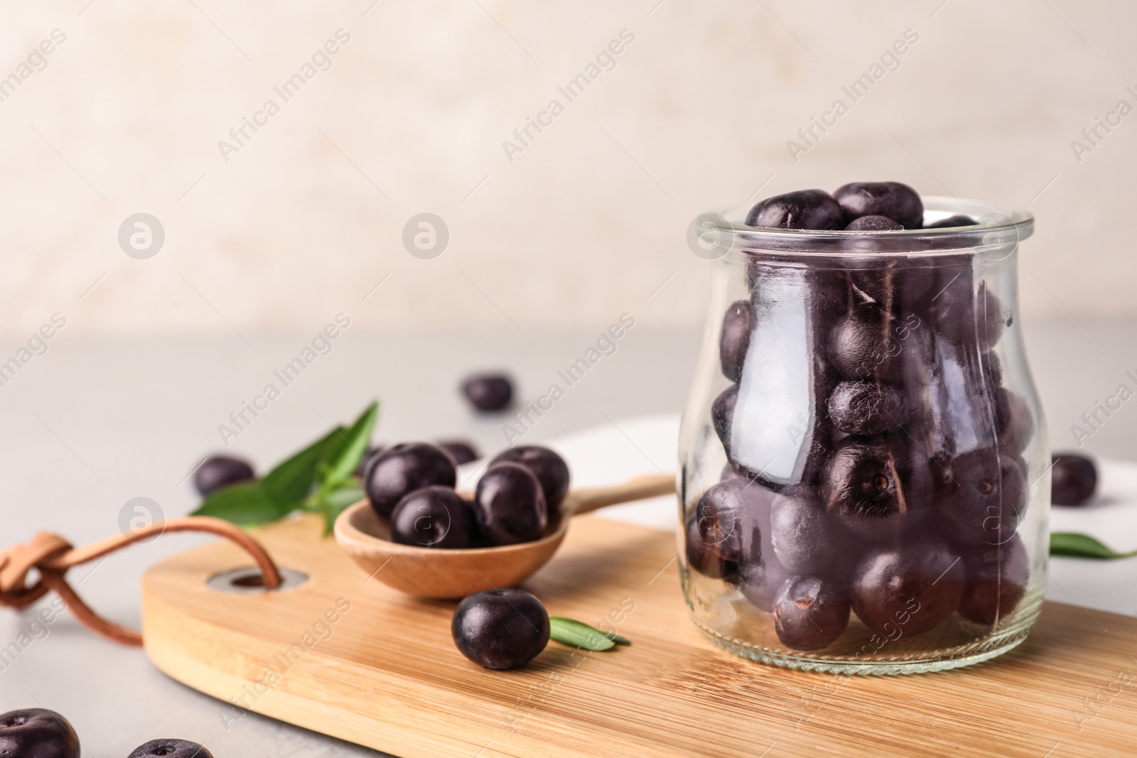 Photo of Jar of fresh acai berries on wooden board, closeup. Space for text