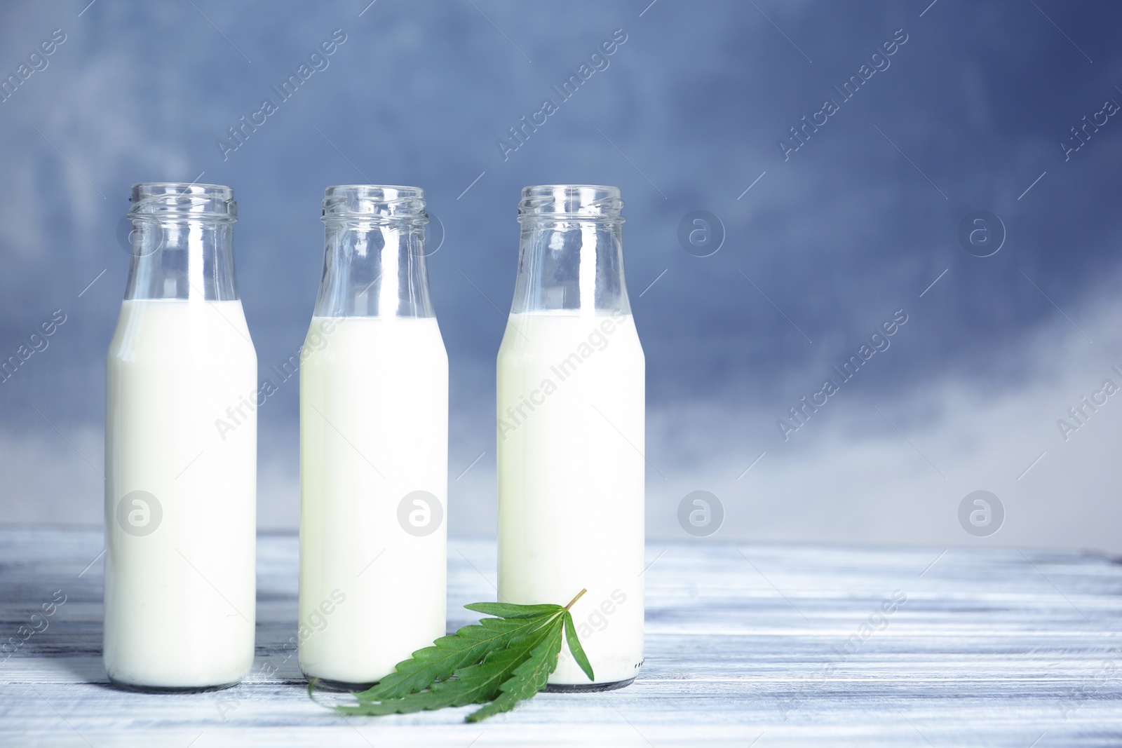 Photo of Glass bottles with hemp milk on table