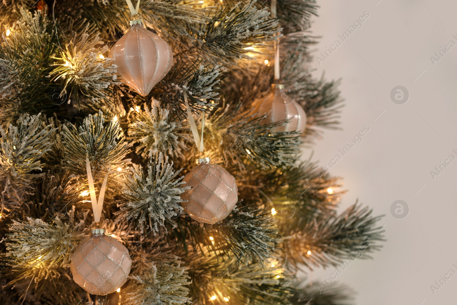 Photo of Christmas tree decorated with holiday baubles and fairy lights, closeup