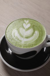 Photo of Cup of fresh matcha latte on wooden table, closeup