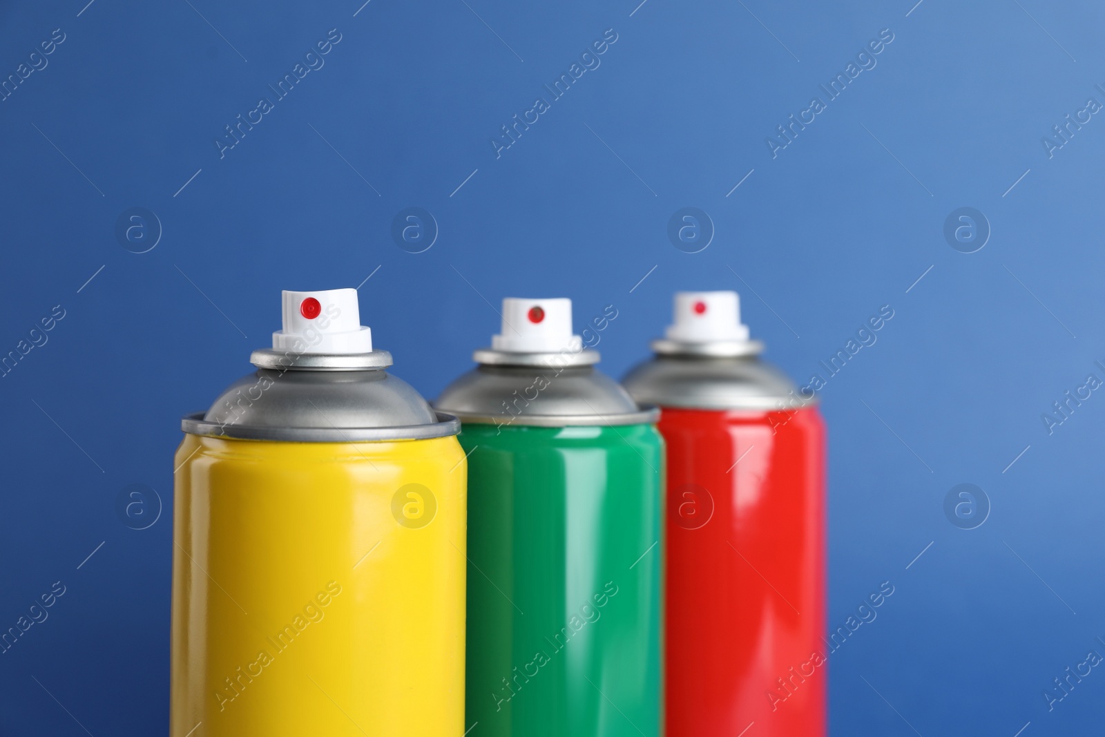 Photo of Colorful cans of spray paints on blue background