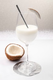Glass of delicious coconut milk and coconut on white table