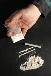 Drug addiction. Man with cocaine and rolled dollar banknote at grey textured table, closeup
