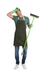 Tired man with green broom on white background