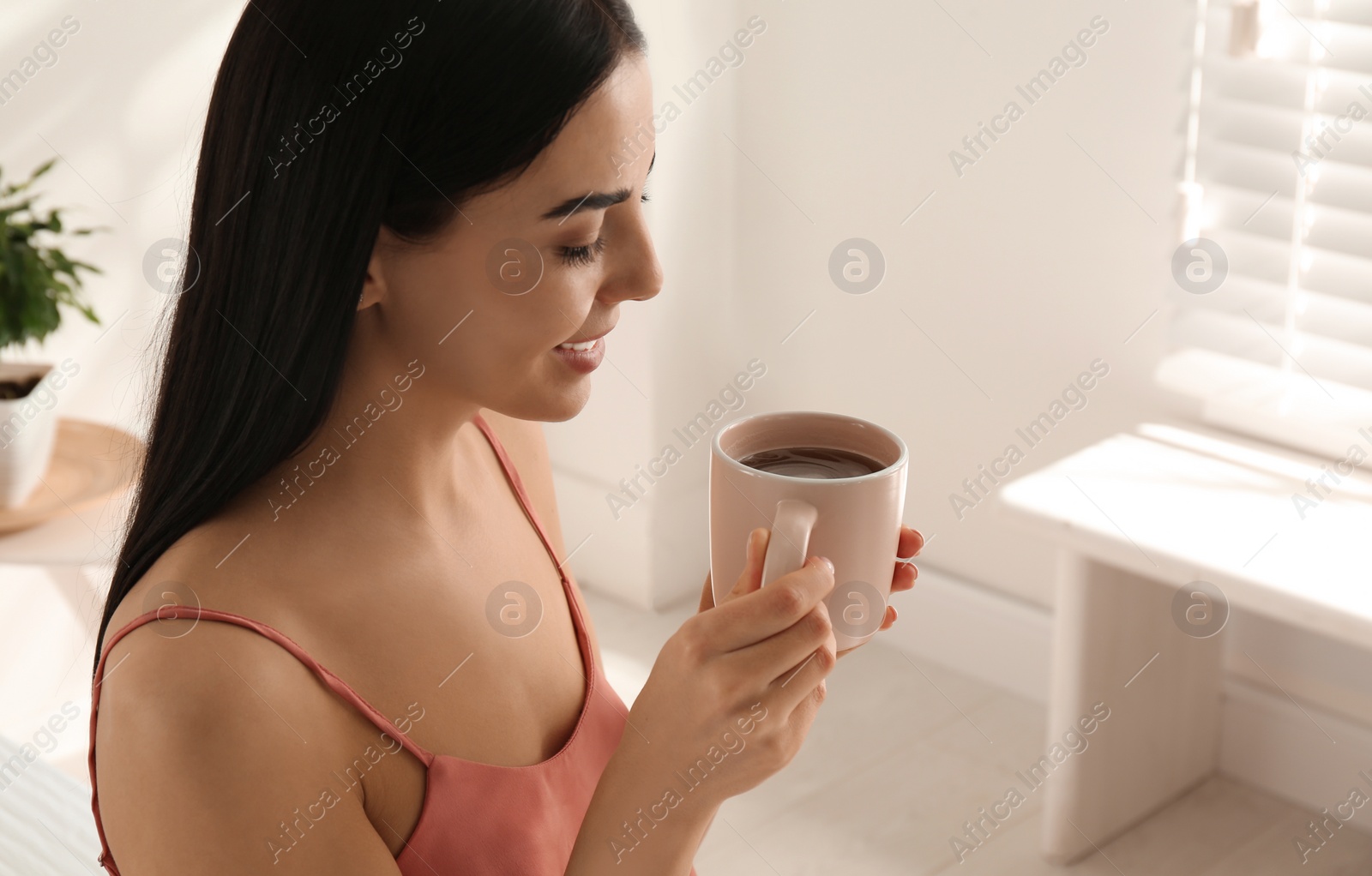 Photo of Woman with cup of tea in bedroom. Lazy morning