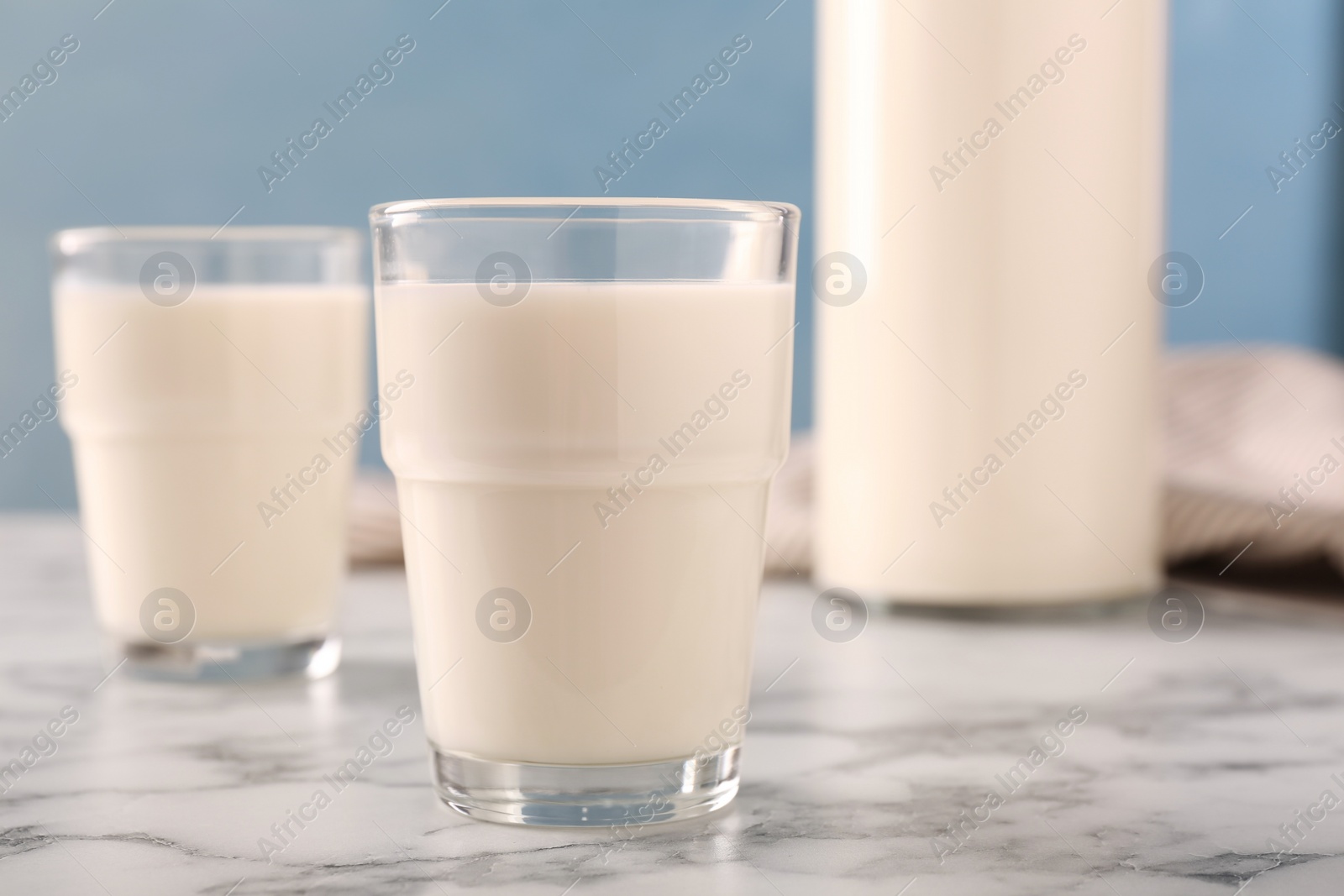 Photo of Glass of fresh milk on white marble table, closeup
