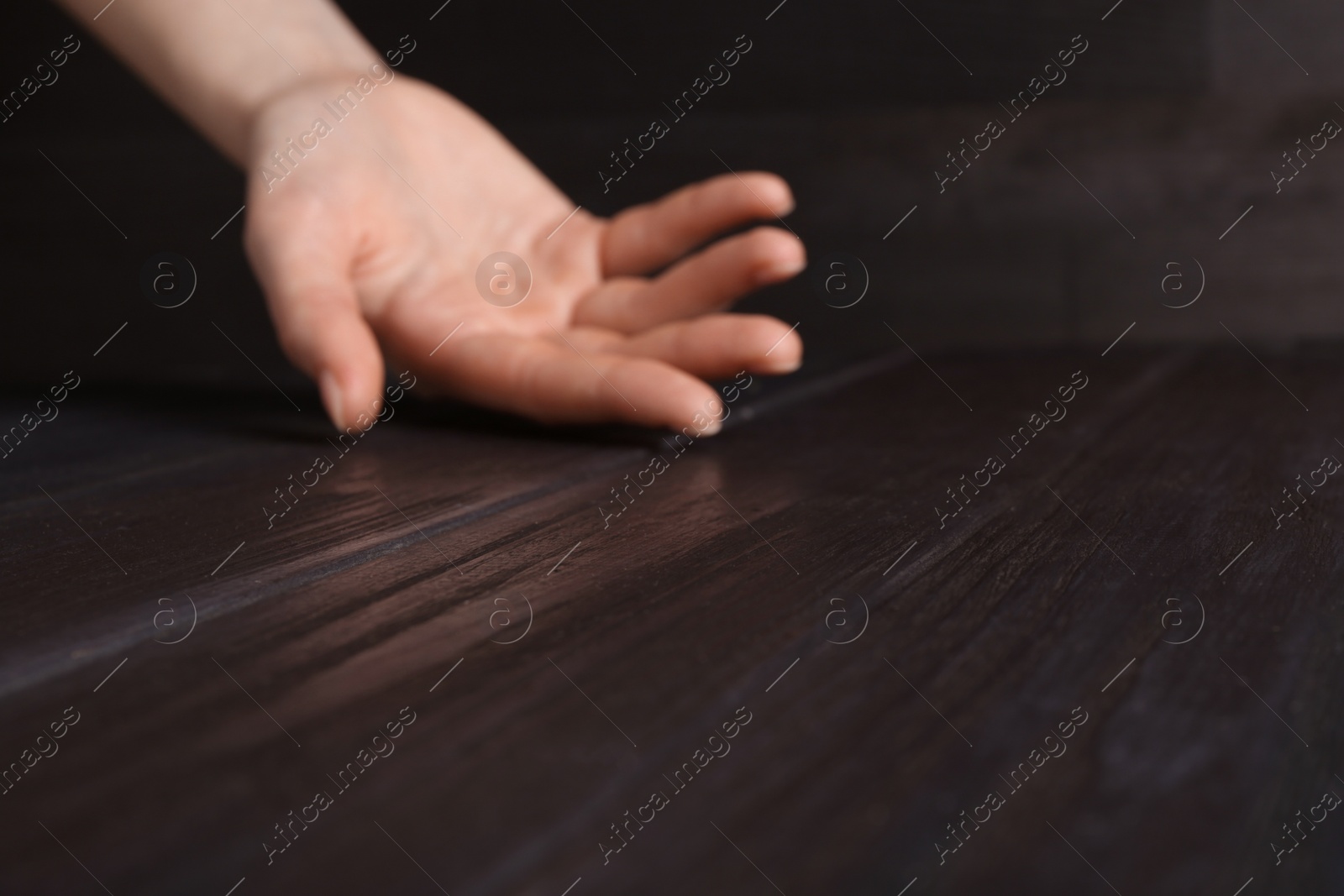 Photo of Woman holding hand above black wooden table, selective focus. Space for text