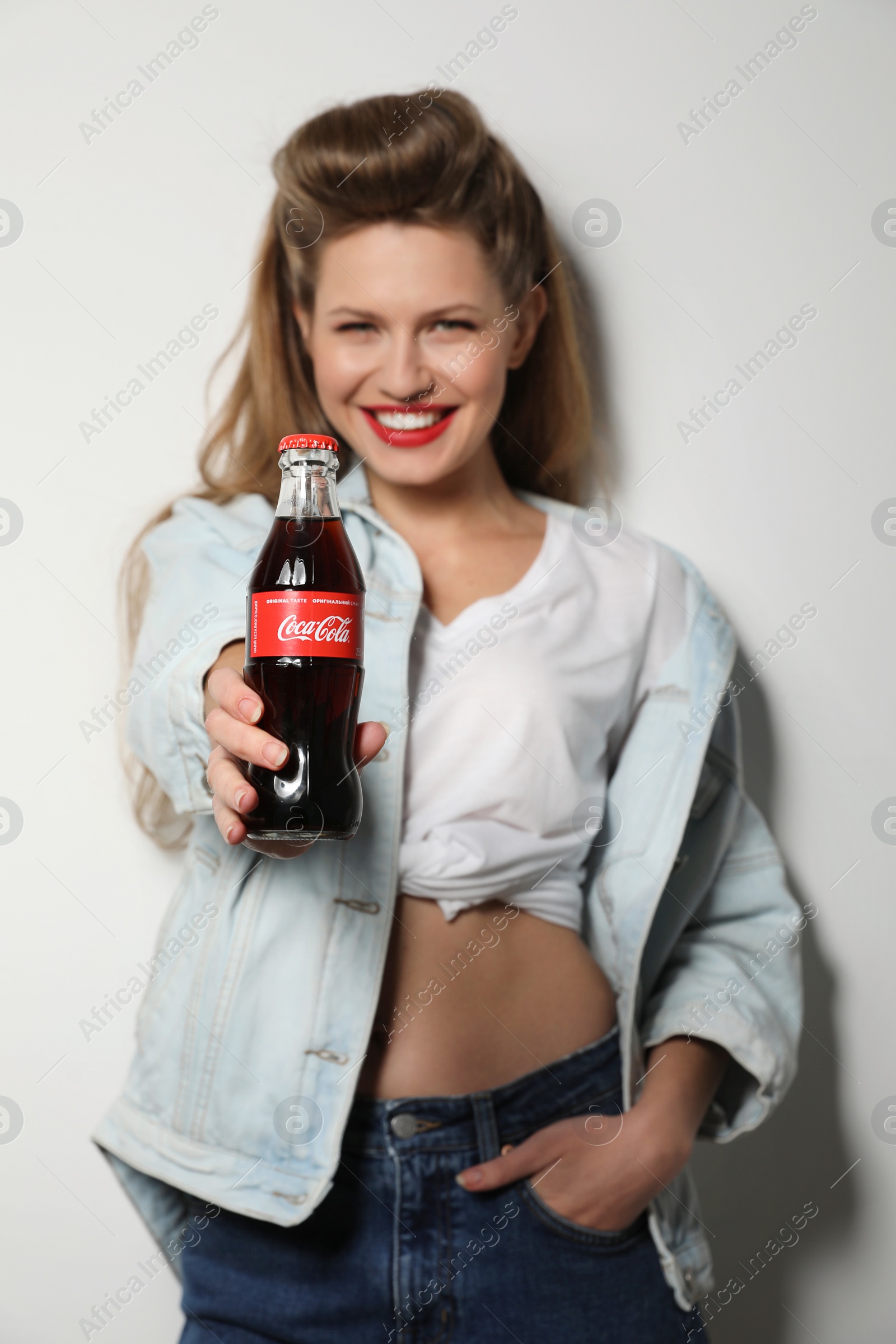 Photo of MYKOLAIV, UKRAINE - NOVEMBER 28, 2018: Young woman with bottle of Coca-Cola on white background