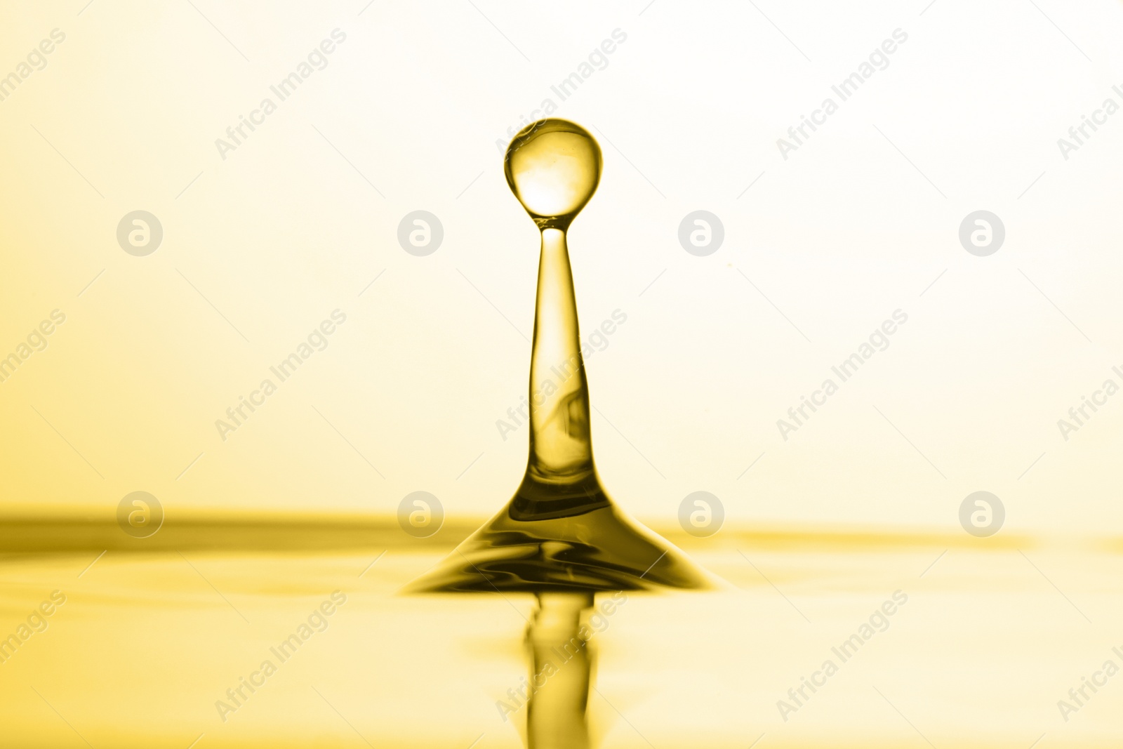 Image of Splash of golden oily liquid on white background, closeup