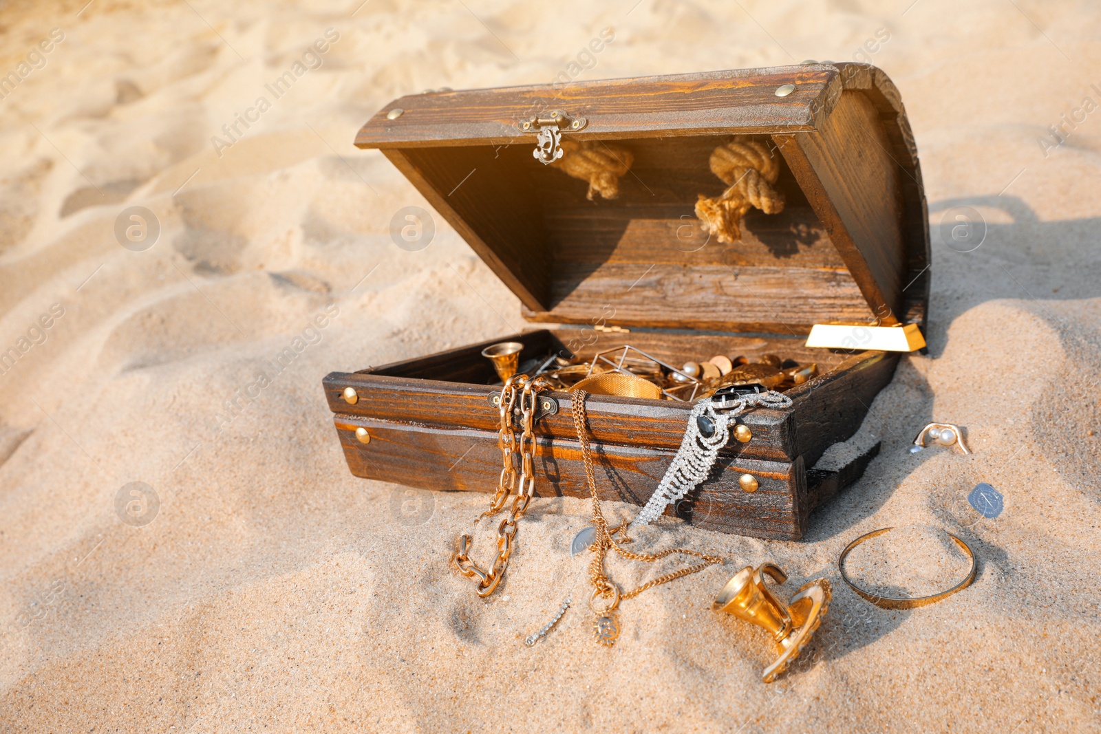 Photo of Open wooden treasure chest on sand, space for text