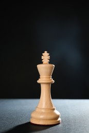 Wooden king on table against dark background, space for text. Chess piece