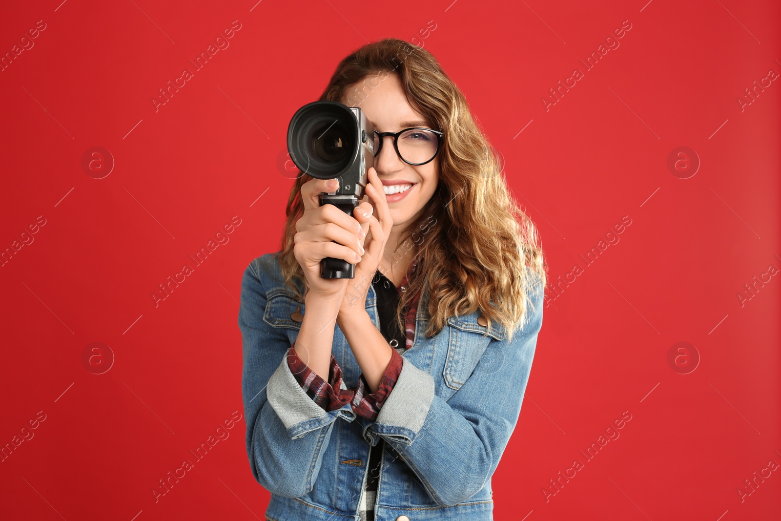 Photo of Beautiful young woman with vintage video camera on red background