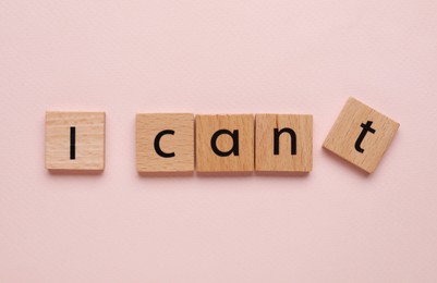 Photo of Motivation concept. Changing phrase from I Can't into I Can by removing square with letter T on pink background, top view