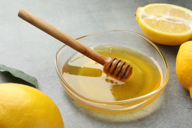 Photo of Sweet honey and fresh lemons on grey table, closeup