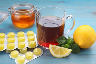 Photo of Cold remedies and cough drops on light blue wooden table, closeup