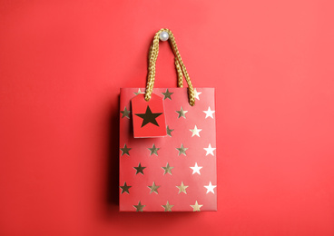 Photo of Shopping paper bag with star pattern on red background