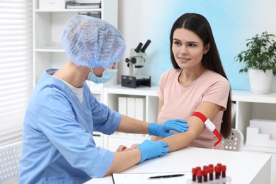 Photo of Laboratory testing. Doctor taking blood sample from patient at white table in hospital