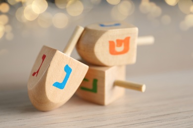 Photo of Hanukkah traditional dreidel with letters Nun and Gimel on wooden table, closeup