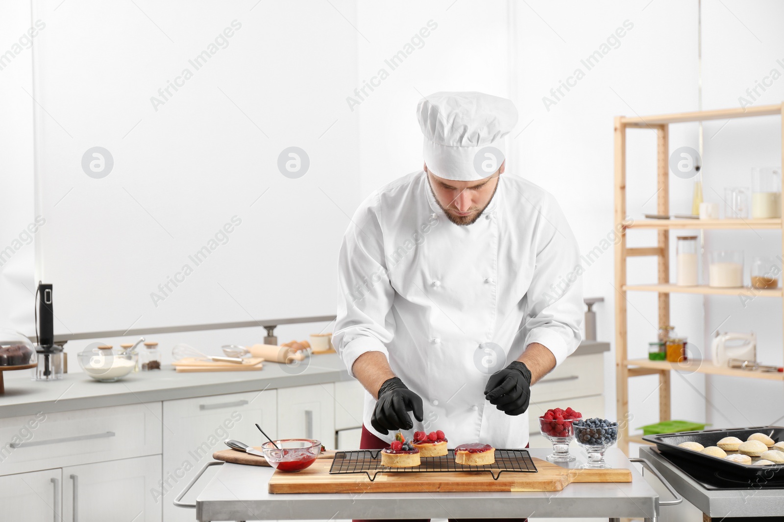 Photo of Male pastry chef preparing desserts at table in kitchen