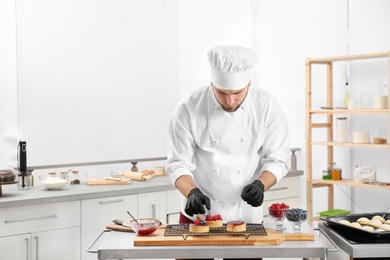 Photo of Male pastry chef preparing desserts at table in kitchen