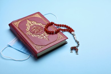 Photo of Muslim prayer beads, Quran and medical mask on light background, space for text
