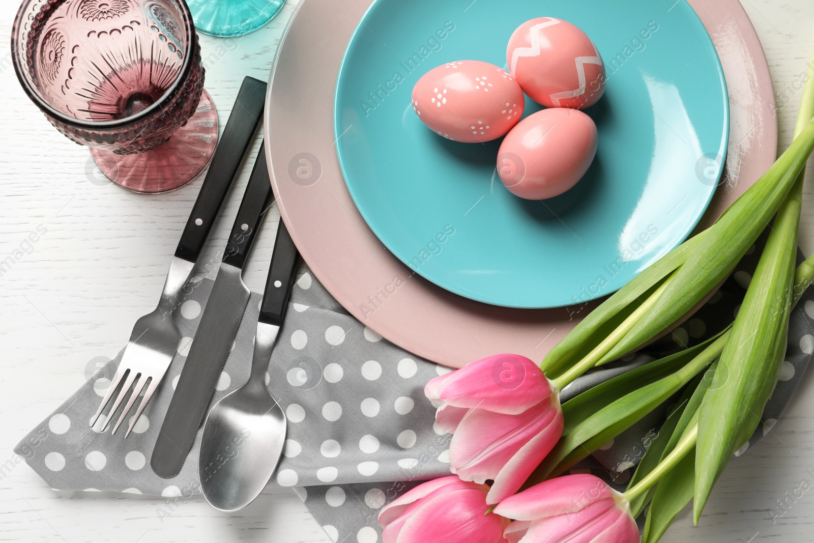 Photo of Festive Easter table setting with painted eggs on wooden background, top view