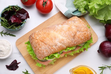 Photo of Delicious sandwich with salmon and ingredients on white table, flat lay