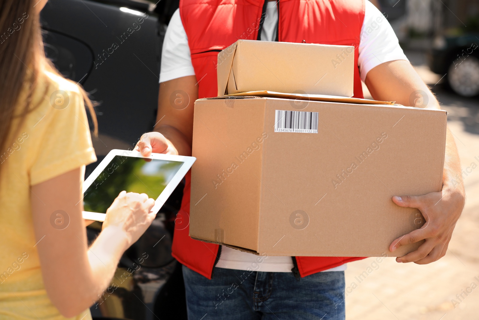 Photo of Woman using app to confirm delivery of parcel from courier outdoors, closeup