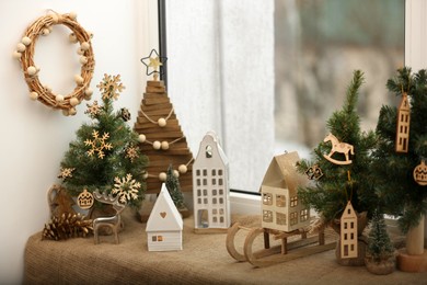 Photo of Beautiful window sill decorated for Christmas with small houses and fir trees indoors