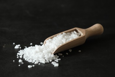 Organic salt and wooden scoop on black table