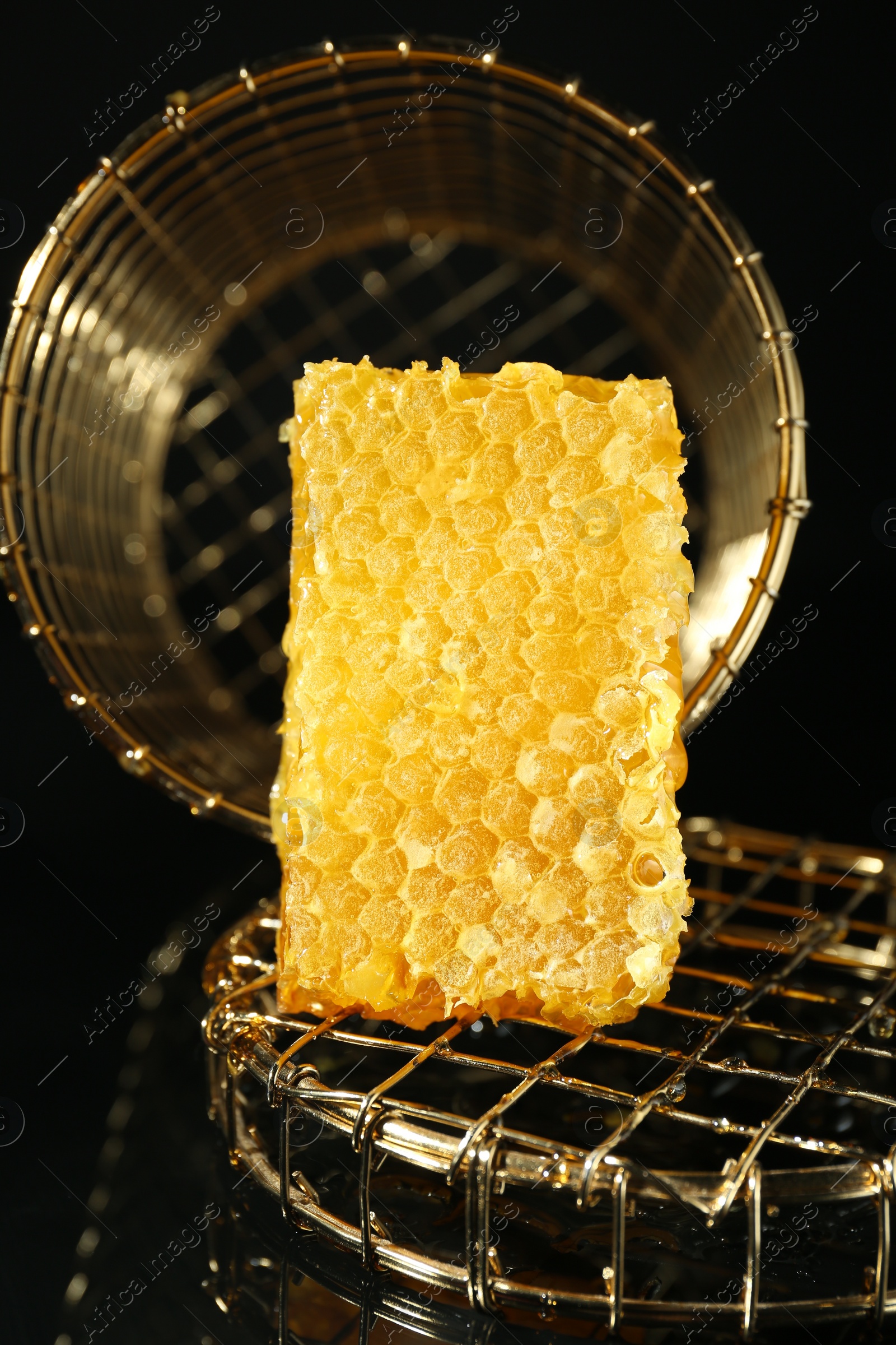 Photo of Piece of natural honeycomb with tasty honey on black background