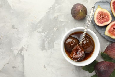 Photo of Bowl of tasty sweet jam and fresh figs on grey table, flat lay. Space for text