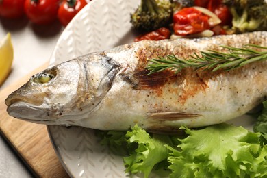 Photo of Delicious baked fish and vegetables on table, closeup