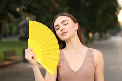 Photo of Woman with hand fan suffering from heat outdoors