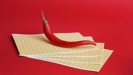 Photo of Pepper plasters and chili on red background. Alternative medicine
