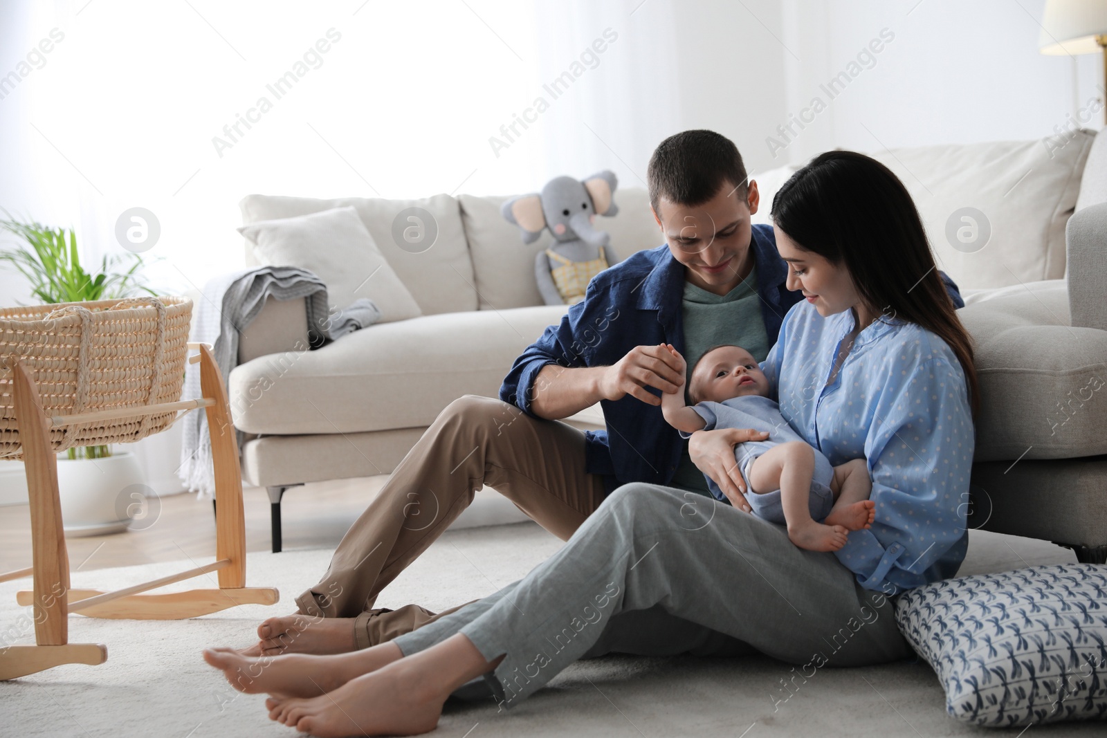 Photo of Happy family with cute baby near sofa at home